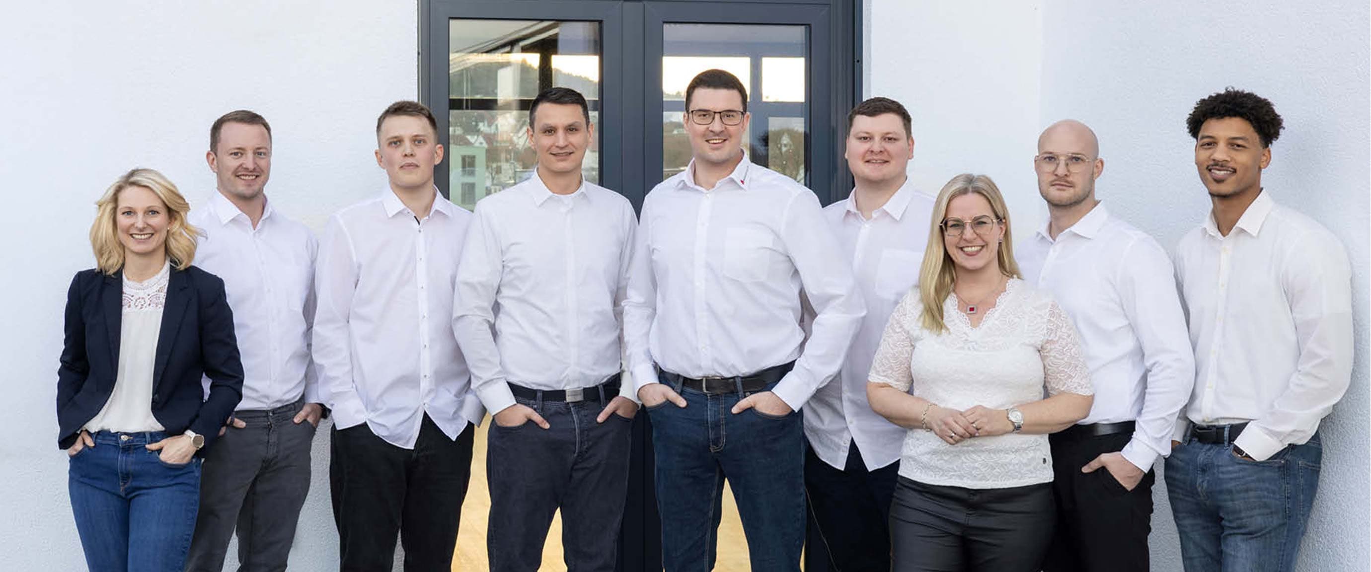 Group photo of the RedCastle team in front of a modern office building. Nine team members are standing together at the building entrance.